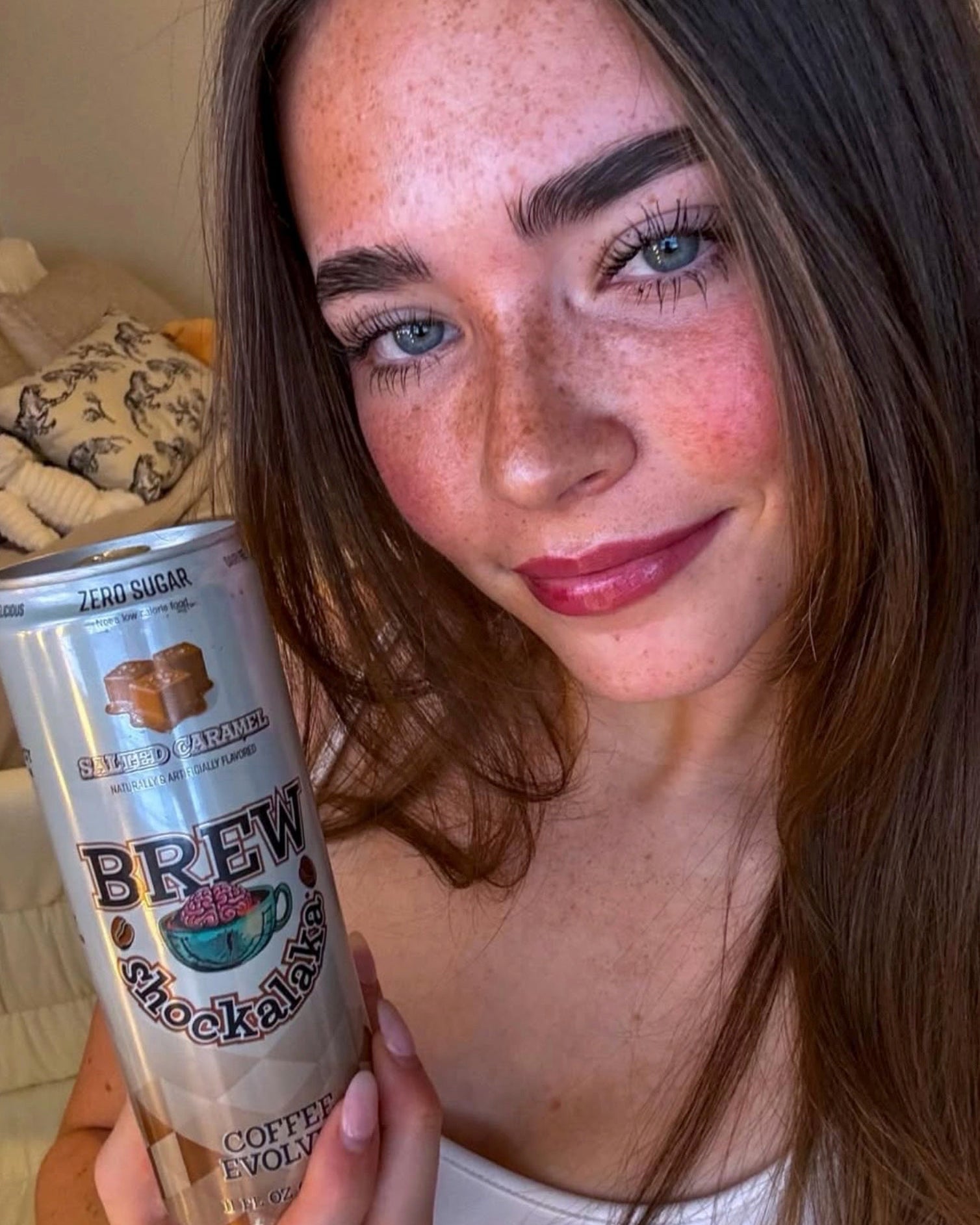 Woman holding a can of 'Brew Coffee' with a blurred background